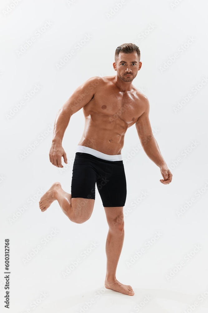 Man athletic body bodybuilder in briefs with naked torso abs full-length in the background, fitness classes. Advertising, sports, active lifestyle, competition, challenge concept.