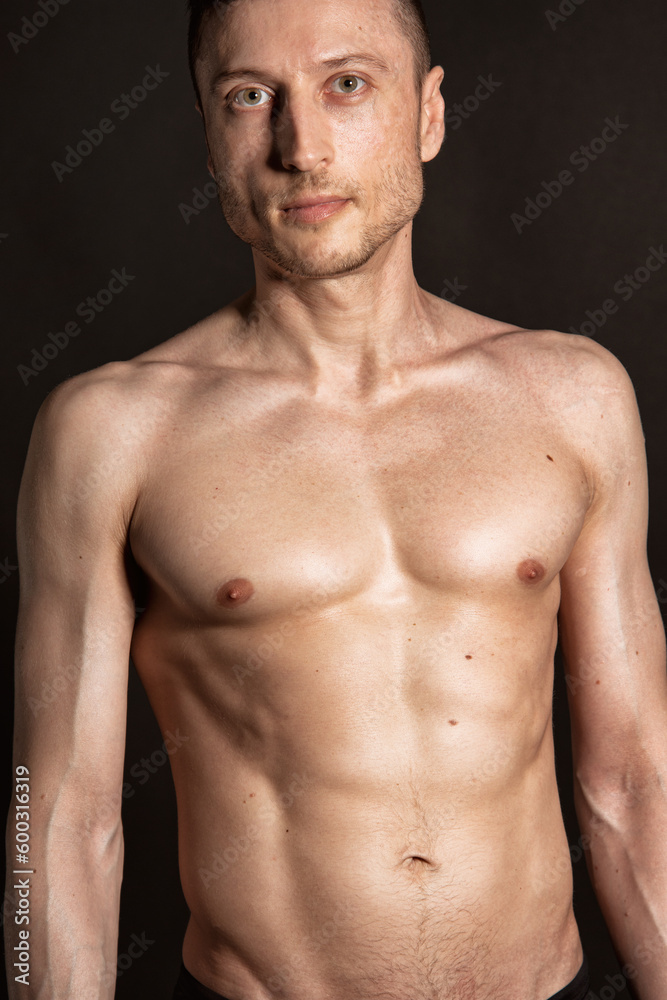 Young attractive man with an athletic body on a black background.