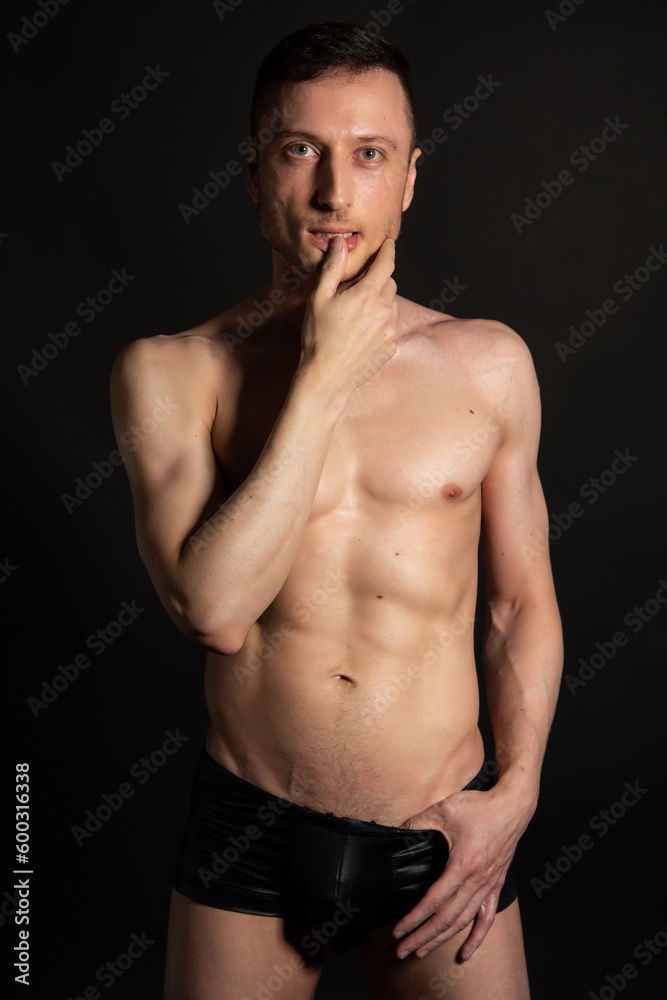 Young attractive man with an athletic body on a black background. Young attractive man with an athletic body on a black background.
