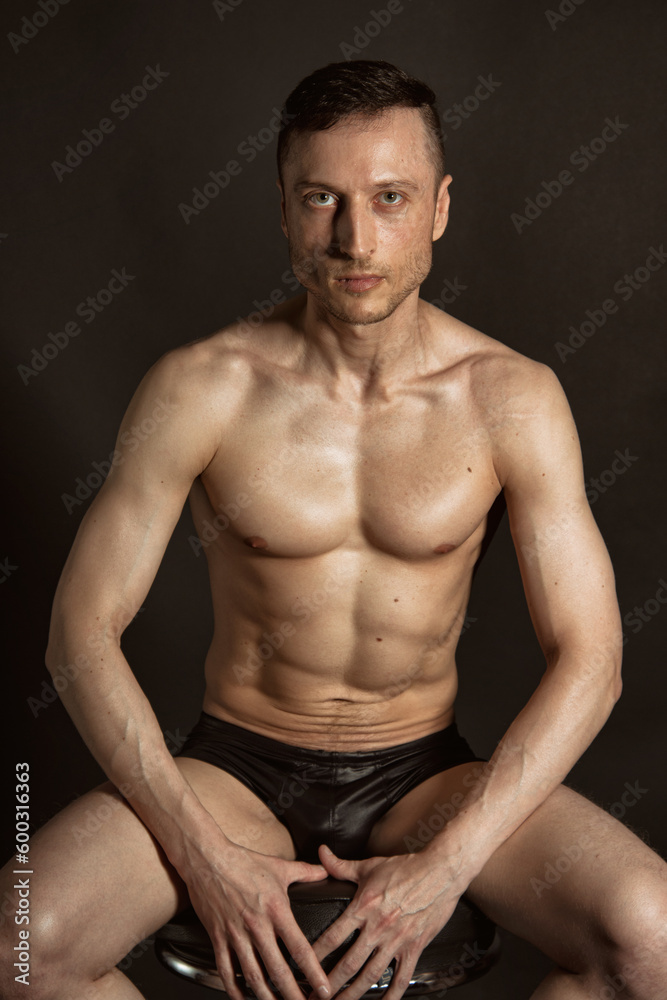 Young attractive man with an athletic body on a black background. Young attractive man with an athletic body on a black background.