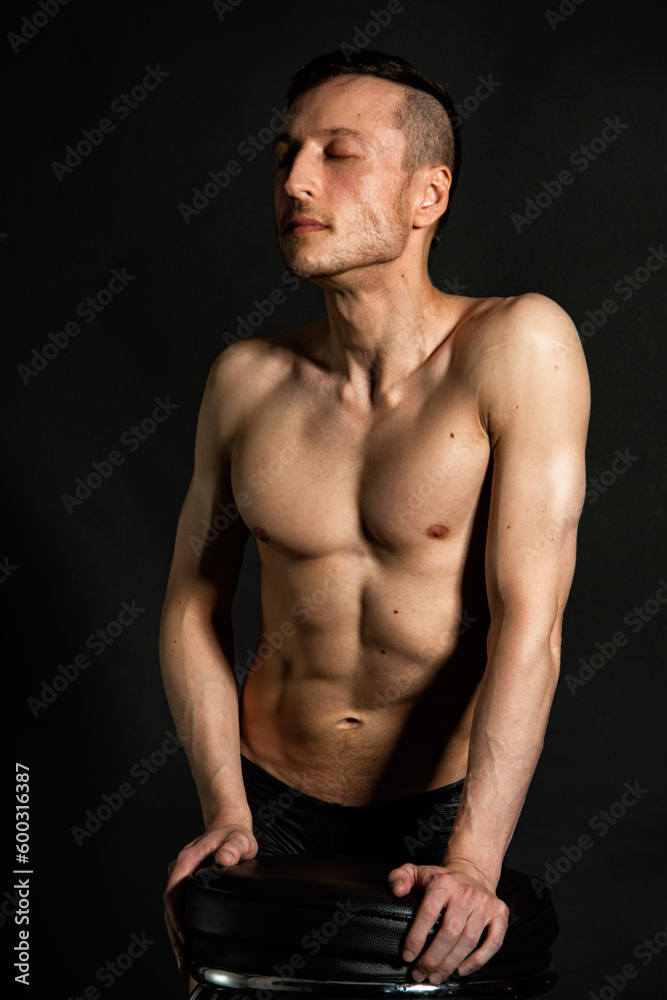 Young attractive man with an athletic body on a black background. Young attractive man with an athletic body on a black background.