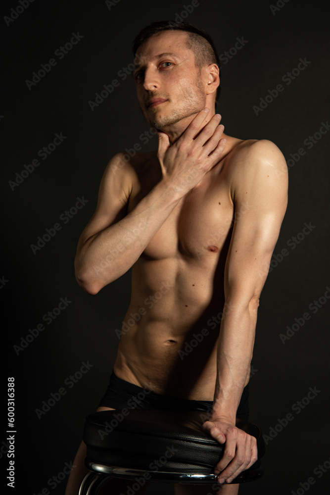 Young attractive man with an athletic body on a black background.