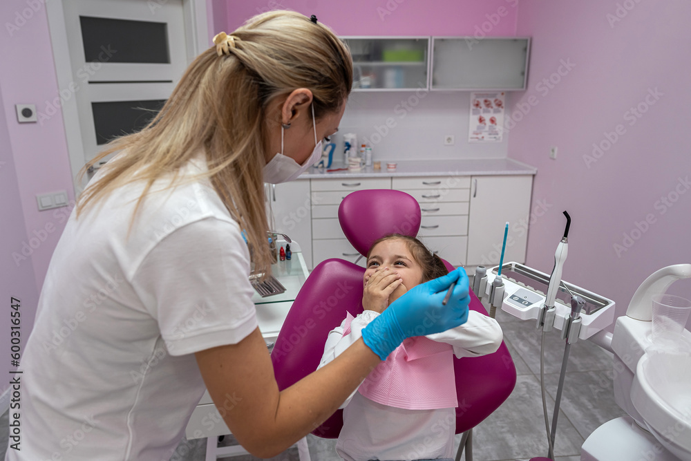girl is sitting dental chair does not want to treat her teeth by showing appropriate gestures