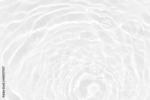 White water with ripples on the surface. Defocus blurred transparent white colored clear calm water surface texture with splashes and bubbles. Water waves with shining pattern texture background.