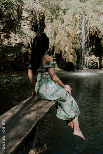 Fototapeta Naklejka Na Ścianę i Meble -  Beautiful model in a turquoise dress posing near a mountain waterfall.Wildlife concept