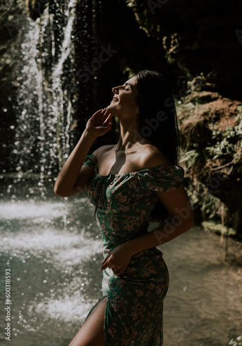 Beautiful model in a turquoise dress posing near a mountain waterfall.Wildlife concept