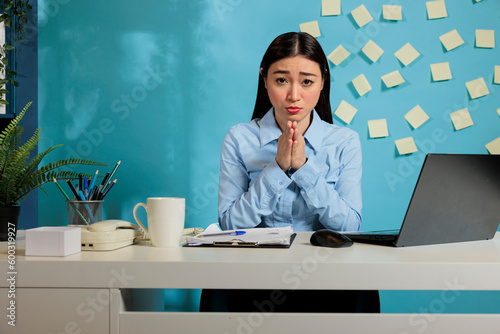 Fotografie Asian woman making pleading gesture with hands, imploring for salary increase sitting at office desk