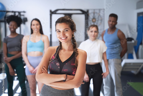 Confident sporty woman standing in front of a group of people at the gym. Sports concept.