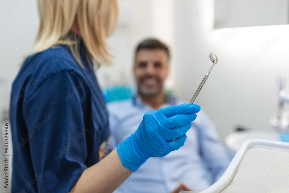 Image of satisfied man sitting in dental chair at medical center while professional doctor fixing his teeth Image of satisfied man sitting in dental chair at medical center while professional doctor fixing his teeth