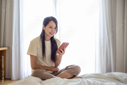 Woman sit on the bed and use of mobile phone