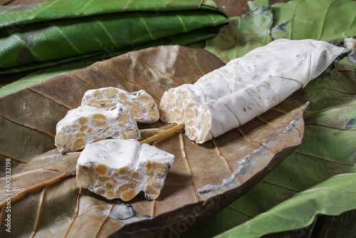 Raw tempeh or tempe. Tempe is fermented from soybeans wrapped with simpo leaf or jati leaf. photo