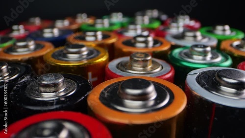 Camera focuses on discarded alkaline batteries, often used in portable electronics. Filmed in macro on a dark surface. photo