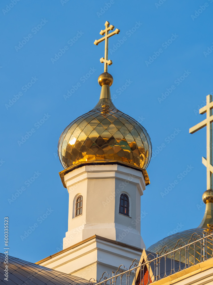 Gilded dome with a cross of an Orthodox church against a blue clear sky