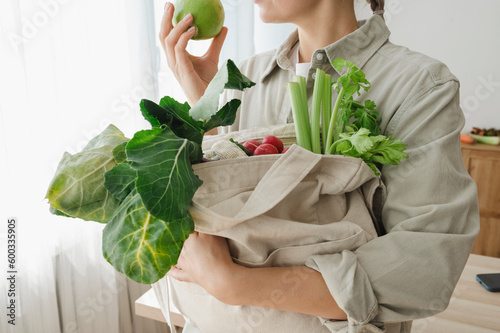 Woman holding reusable bag full of organic vegetables and fruits photo