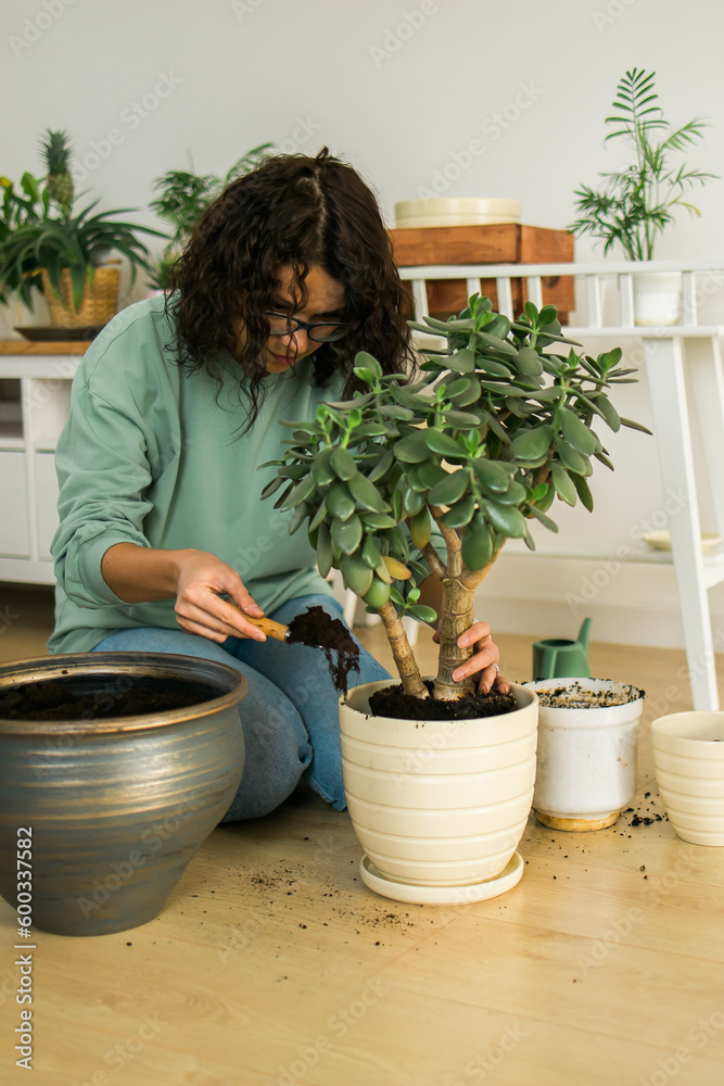 Woman grows potted plants at home watering and take care flowers - gardening and houseplant care concept Woman grows potted plants at home watering and take care flowers - gardening and houseplant care concept