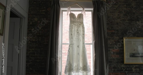 Wedding dress hung on a window in slow motion wide shot photo