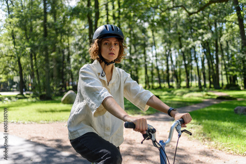 Woman in helmet riding on bicycle at city public park