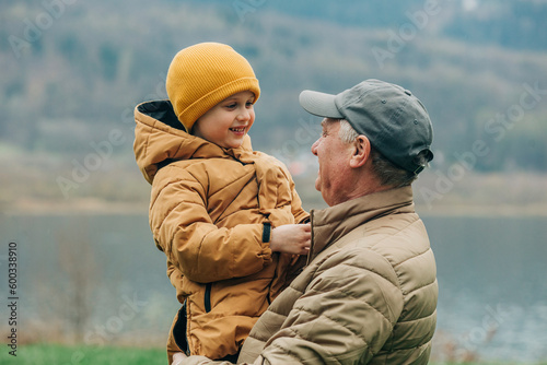 Grandfather carrying grandson wearing warm clothing photo