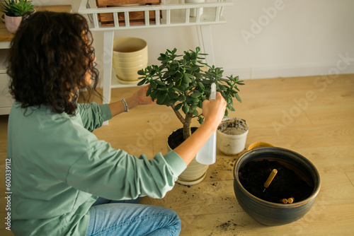 Woman grows potted plants at home watering and take care flowers - gardening and houseplant care concept