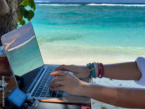 Nomad digital with laptop and running remotely with bright scenic view near poolside on the beach in summer time photo
