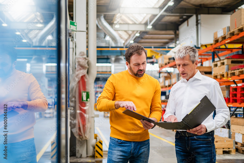 Businessman and manager discussing together in production hall at factory Businessman and manager discussing together in production hall at factory