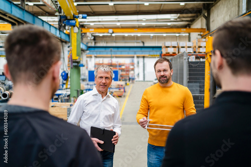 Businessman and manager communicating with employees at factory