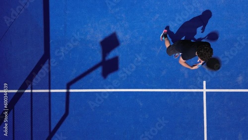 A sequence of overhead top view shots of a young handsome padel player hitting the ball with a smash bandeja vibora on the fly.