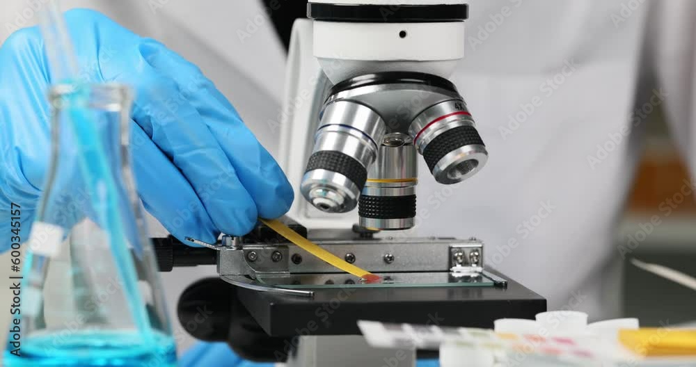 Chemist in laboratory checks ph strips on microscope. Exploring toxic