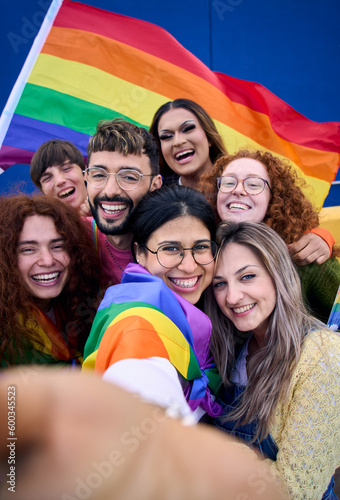 Fotografiet Vertical selfie of LGBT group of young people celebrating gay pride day holding rainbow flag together