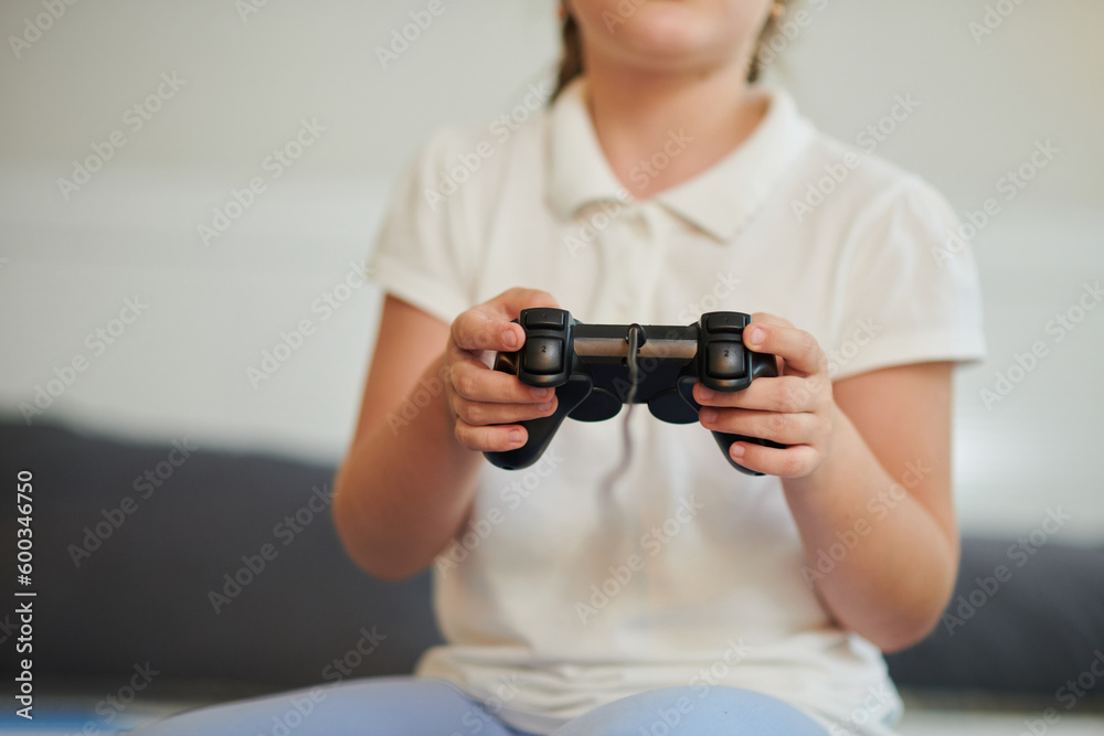 Girl with controller on hands playing video game at home