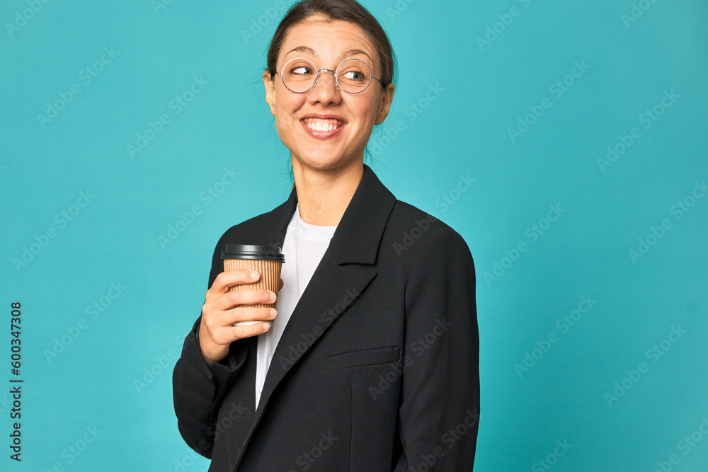 A young caucasian business woman holds a takeaway coffee looks aside smiling, cheerful and pleasant. A young caucasian business woman holds a takeaway coffee looks aside smiling, cheerful and pleasant.