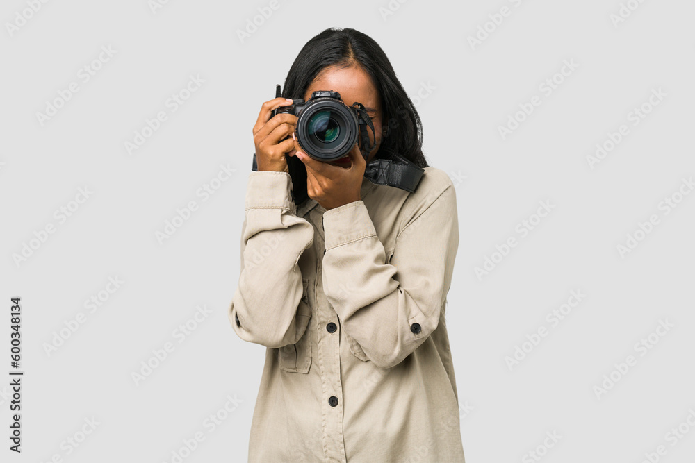 Young Indian photographer woman holding a professional camera isolated - obrazy, fototapety, plakaty 