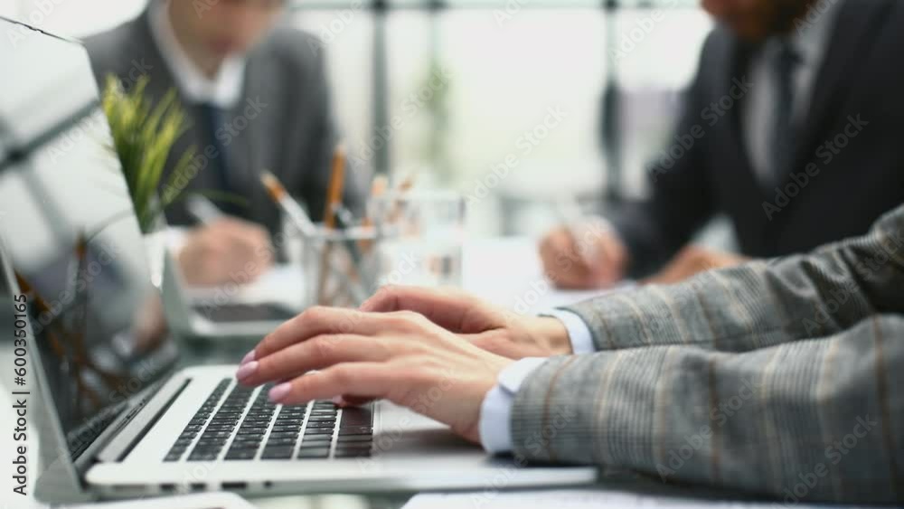 Woman hands pressing keys on a laptop keyboard in office.