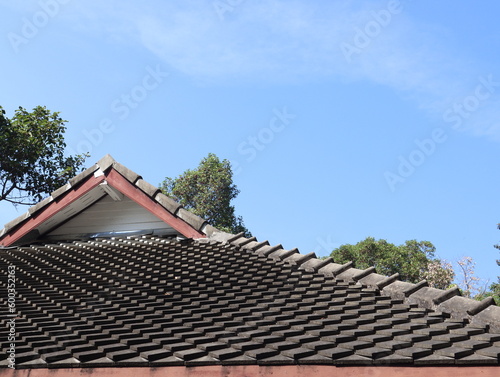 an old house made of gray tile roof against a background of blue sky during the day.