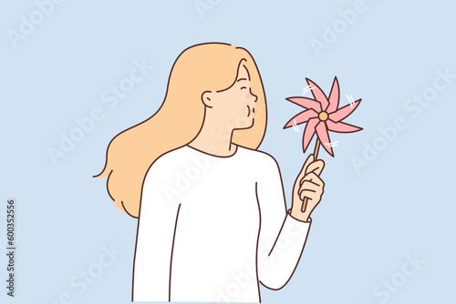 Girl teenager with pinwheel for children in hands blows on toy spinning in wind.