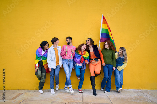 Bild auf Leinwand Portrait of group cheerful young friends standing on wall yellow