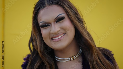 Portrait of excited transgender young with yellow background. Fun queer person posing for photo on gay pride day. LGBT and trans community. Cheerful Drag queen, Latin people isolated with copy space.