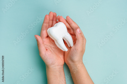 White tooth in the hands of a man. Oral health concept. Teeth whitening. Place for text. Advertising banner.