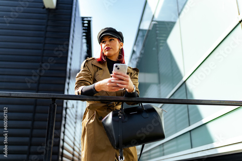 An elegantly dressed business woman with a phone in her hand in front of a business complex