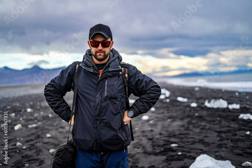 man with serious look at diamond black beach in iceland with pieces of ice on the shore