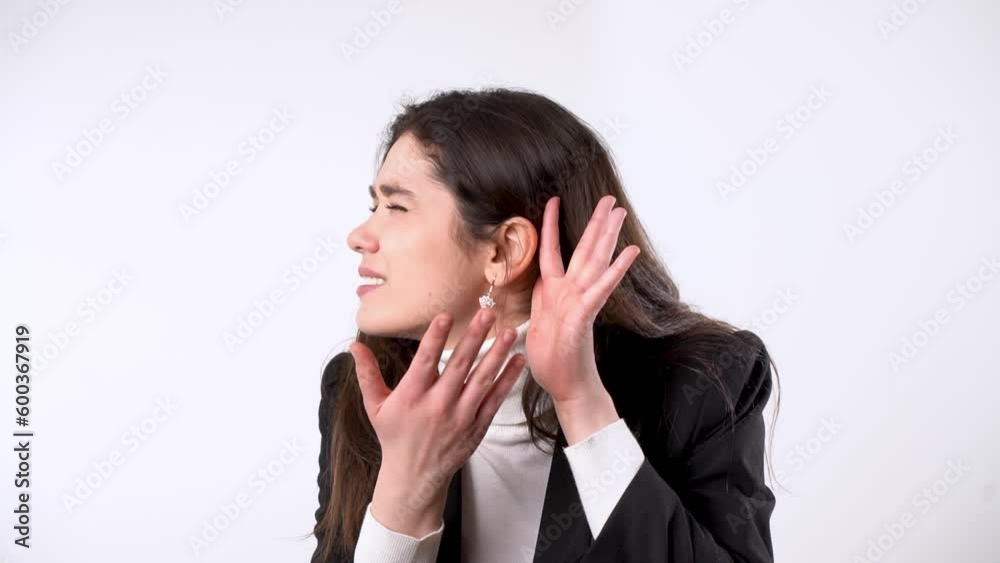 Interested young woman in elegant jacket putting hand to ear and trying to hear while showing listening gesture on white background Interested young woman in elegant jacket putting hand to ear and trying to hear while showing listening gesture on white background