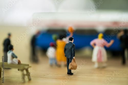 Close up miniature toy figurines of a group passengers waiting at a platform