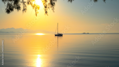 Early morning on calm sea, orange sky and sailing yacht, calmness, serenity and meditation photo