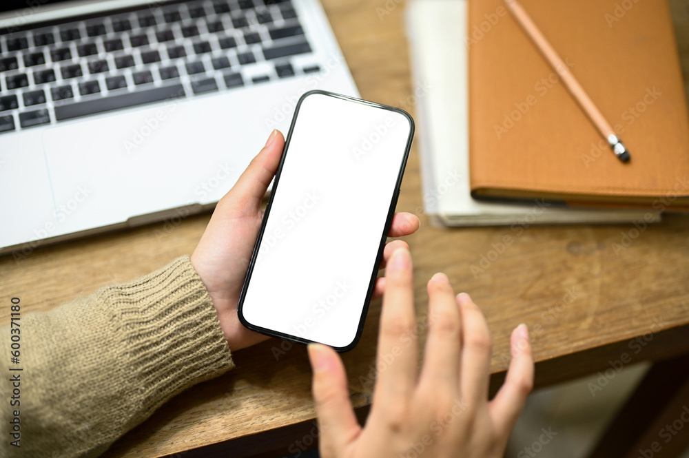 Close-up shot of a woman in cozy sweater using her smartphone at her workspace. Close-up shot of a woman in cozy sweater using her smartphone at her workspace.