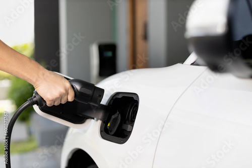 Progressive concept of hand insert an emission-free power connector to the battery of electric vehicle at home. Electric vehicle charging via cable from charging station to EV car battery