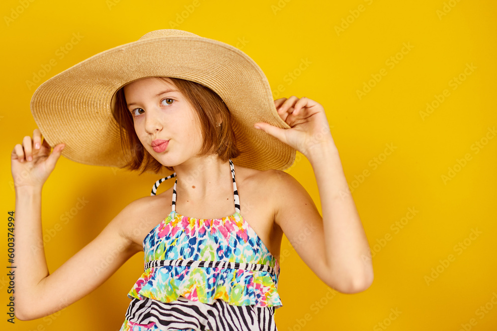 Child teenager girl in swimsuit and straw hat posing