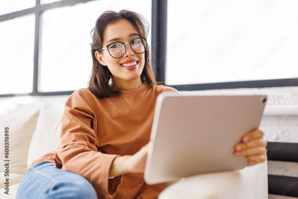 beautiful young woman uses tablet while sitting on sofa beautiful young woman uses tablet while sitting on sofa