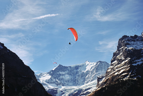 Paragliding in the mountains with some clouds in Swiss Alps