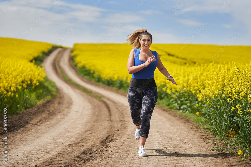 Plus size woman running on a countryside dirt road Plus size woman running on a countryside dirt road