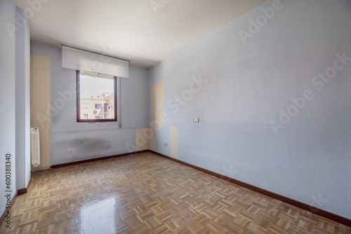 An empty room with damask parquet flooring with red aluminum window and soft white blind